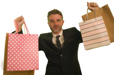 isolated background portrait of young attractive and happy business man in suit and tie holding lot of shopping bags smiling cheerful in sales and opportunity concept 