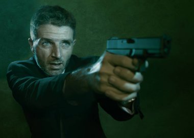 Man pointing handgun dramatic action portrait of attractive special agent or police officer aiming with gun in suit and tie holding the weapon serious in law enforcement