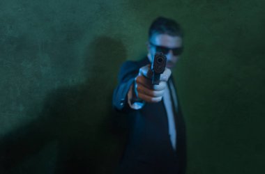 Man pointing handgun dramatic action portrait of attractive special agent or police officer aiming with gun in suit and tie holding the weapon serious in law enforcement