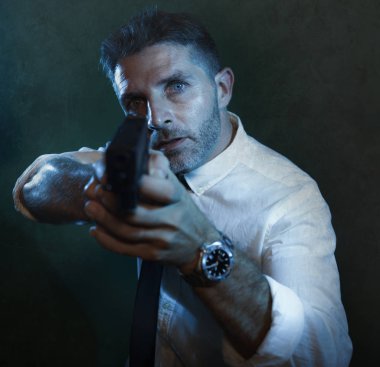 Man pointing handgun - dramatic action portrait of attractive special agent or police officer aiming with gun in white shirt and tie holding the weapon serious in law enforcement