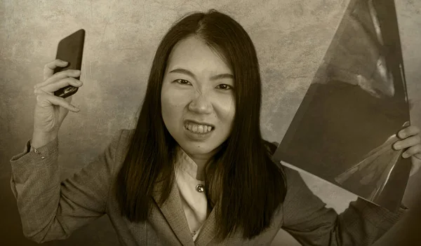business stress portrait of young attractive upset and stressed executive Asian Korean woman tired and unhappy holding paperwork overwhelmed screaming desperate