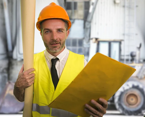 Bouwwerk levensstijl portret van jonge gelukkige en aantrekkelijke ingenieur of aannemer met blauwdrukken dragen bouwvakker hardhat glimlachen zelfverzekerd — Stockfoto