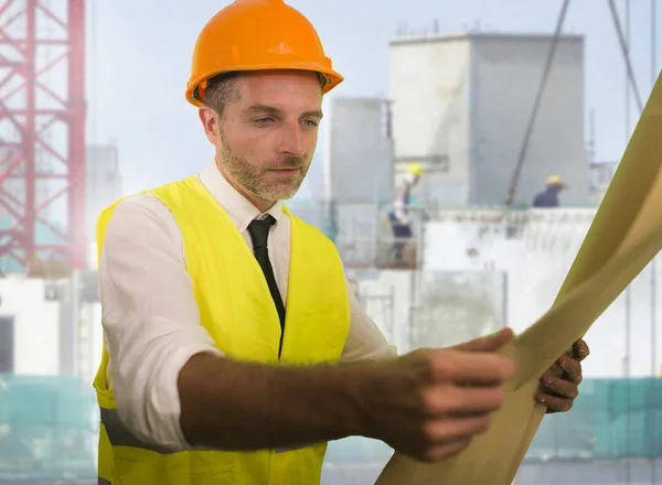 Bouwwerk levensstijl portret van jonge gelukkige en aantrekkelijke ingenieur of aannemer met blauwdrukken dragen bouwvakker hardhat glimlachen zelfverzekerd — Stockfoto