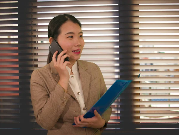 オフィスビジネスライフスタイルの肖像画美しいと成功したアジア系韓国人女性エグゼクティブ服の笑顔ヴェネツィアブラインドウィンドウで携帯電話で話して — ストック写真