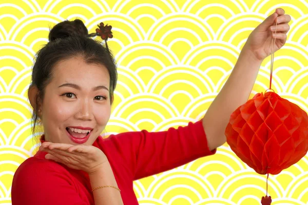 Gelukkig portret van jonge mooie en zoete Aziatische Chinese vrouw in traditionele broodje haar stijl en rode jurk met lantaarn vieren Nieuwjaar in China geïsoleerd in goud — Stockfoto