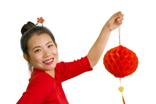 Νεαρή όμορφη και ευτυχισμένη ασιατική κινεζική κορίτσι σε παραδοσιακό bun στυλ μαλλιών και κόκκινο φόρεμα κρατώντας φανάρι γιορτάζει το νέο έτος στην Κίνα απομονωμένο σε λευκό φόντο χαμογελώντας χαρούμενα — Φωτογραφία Αρχείου