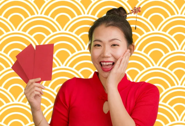 Jong gelukkig en mooi aziatisch Chinees meisje in traditionele Nieuwjaar rode jurk en haar broodje met rode zak enveloppen met geld als zegen van vrienden en familie — Stockfoto