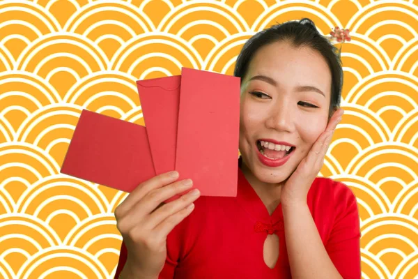 Jong gelukkig en mooi aziatisch Chinees meisje in traditionele Nieuwjaar rode jurk en haar broodje met rode zak enveloppen met geld als zegen van vrienden en familie — Stockfoto