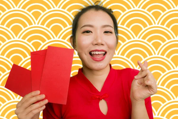 Jong gelukkig en mooi aziatisch Chinees meisje in traditionele Nieuwjaar rode jurk en haar broodje met rode zak envelop met geld als zegen van vrienden en familie — Stockfoto