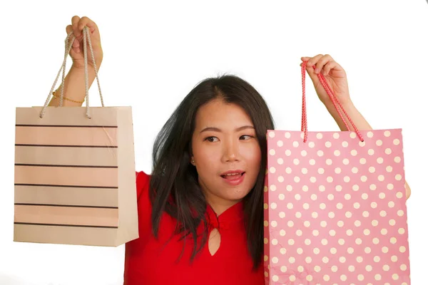 Młody szczęśliwy i piękny Azji koreański kobieta w czerwony strój uśmiechnięty wesoły gospodarstwa torby na zakupy jako podekscytowany zakupoholiczka dziewczyna odizolowany na białym tle w piękno moda koncepcja — Zdjęcie stockowe