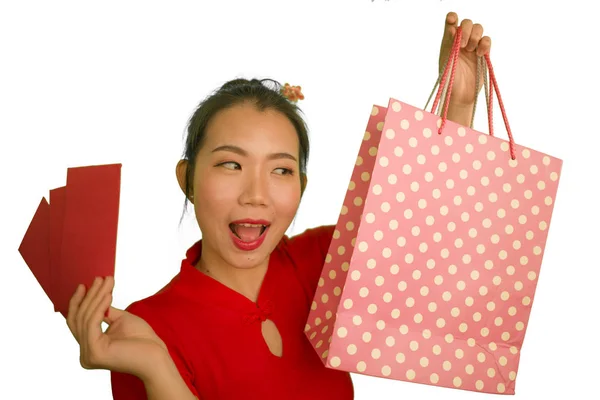 Joven feliz y hermosa mujer coreana asiática en vestido rojo sonriente alegre celebración bolsas de compras como dinero gastado emocionado después de recibir chino de Año Nuevo bolsillo rojo con dinero — Foto de Stock