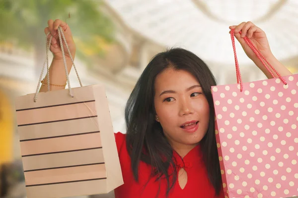 Lifestyle portrait of young beautiful and happy Asian Korean woman holding shopping bags at modern shopping mall smiling excited and cheerful in shopaholic girl crazy about fashion — 스톡 사진