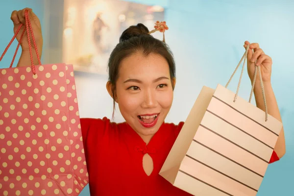 Estilo de vida retrato de la joven hermosa y feliz mujer china asiática sosteniendo bolsas de compras en el centro comercial moderno sonriendo emocionado y alegre en shopaholic chica loca por la moda — Foto de Stock