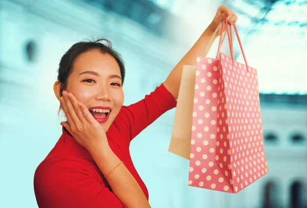 Retrato de estilo de vida de jovem bela e feliz mulher chinesa asiática segurando sacos de compras no shopping center moderno sorrindo animado e alegre na shopaholic menina louca sobre a moda — Fotografia de Stock