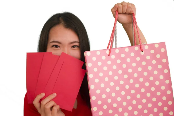 Joven feliz y hermosa mujer asiática en vestido rojo sonriente alegre celebración bolsas de compras como dinero gastado emocionado después de recibir chino de Año Nuevo bolsillo rojo con dinero aislado — Foto de Stock