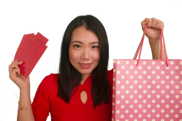 Kırmızı elbiseli, mutlu ve güzel Asyalı bir kadın. Elinde alışveriş poşetleri tutarken gülümsüyor. Çin Yeni Yılı 'nın kırmızı cebi ve izole edilmiş paraları aldıktan sonra para harcamak kadar heyecanlı. — Stok fotoğraf