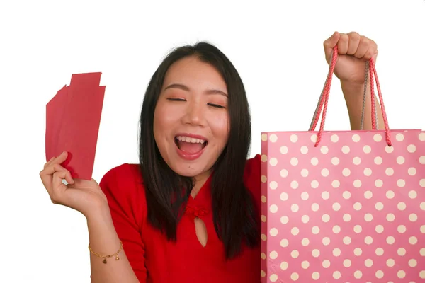 Joven feliz y hermosa chica asiática en vestido rojo sonriente alegre celebración bolsas de compras como dinero gastado emocionado después de recibir chino de Año Nuevo bolsillo rojo con dinero aislado — Foto de Stock