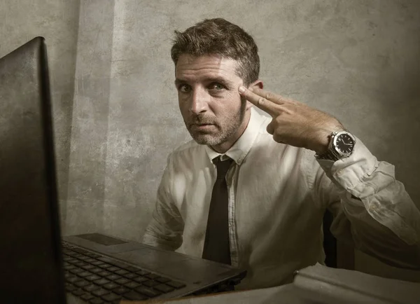 Corporate business work stress - young desperate and frustrated businessman working stressed and overwhelmed at office computer desk pointing hand like a gun — 스톡 사진