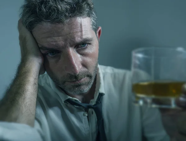 Αλκοολικός άντρας με γραβάτα χάνει πίνοντας αλκοόλ απελπισμένος και χαμένος κοιτάζοντας ένα ποτήρι ουίσκι σκεπτόμενος μεθυσμένος και μελαγχολικός πέφτοντας πάνω στον εθισμό στο ποτό — Φωτογραφία Αρχείου