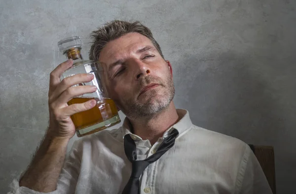 Alcoholic man in lose necktie drinking alcohol desperate and wasted holding whiskey bottle feeling drunk and depressed drinking to evade reality in grunge edit — 스톡 사진