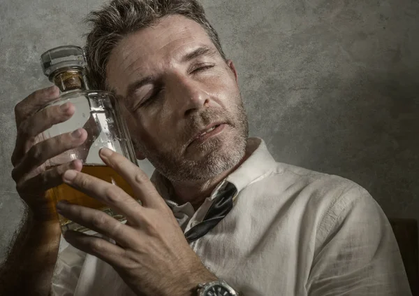 Alkolik kravatlı, alkollü içki içen, elinde viski şişesi tutan sarhoş ve bunalımlı bir adam grunge editörlüğünde gerçeklerden kaçmak için içiyor. — Stok fotoğraf