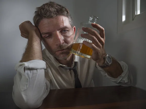 Dramatyczny portret pijanego mężczyzny po trzydziestce do czterdziestki w krawacie pijącego alkohol zdesperowany i zmarnowany trzymającego butelkę whisky z poczuciem mdłości i depresji pijącego, by uniknąć rzeczywistości — Zdjęcie stockowe