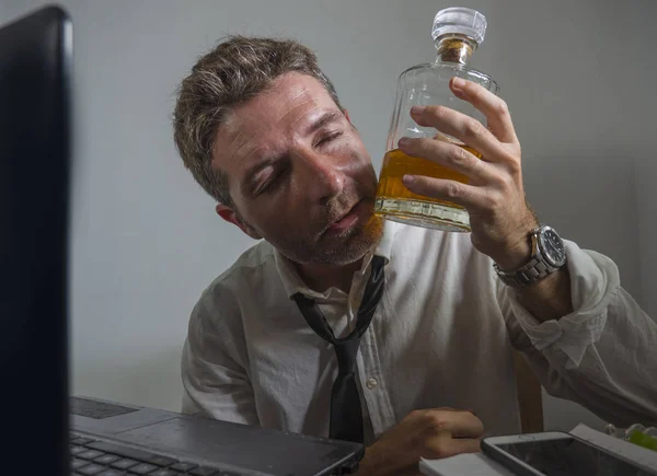 Biznesmen uzależniony od alkoholu - dramatyczny portret alkoholika w krawacie, pijącego w biurze, pracującego pijanego i przygnębionego, trzymającego butelkę whisky — Zdjęcie stockowe