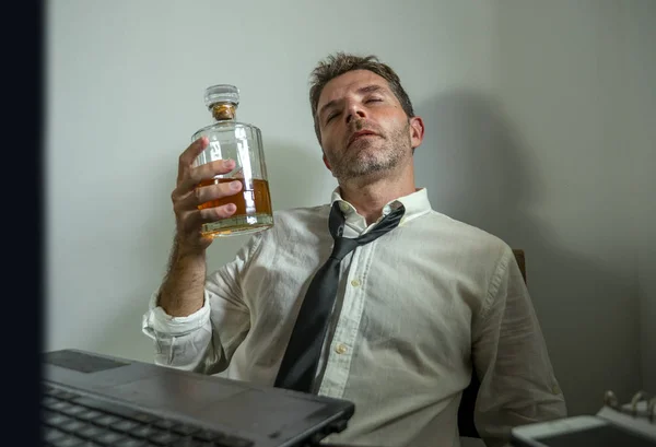 Viciado em álcool empresário - retrato dramático de homem alcoólico em perder gravata beber na mesa de escritório enquanto trabalhava desperdiçado e bagunçado segurando garrafa de uísque bêbado e deprimido — Fotografia de Stock