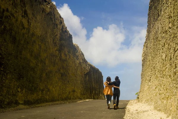Back view young happy and beautiful couple in love enjoying outdoors journey walking playful in cliff rock road exploring the landscape together in holidays travel adventure — 스톡 사진