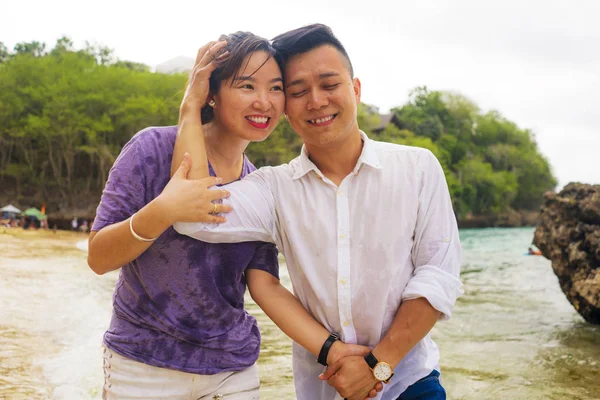 Summer holidays lifestyle portrait of young beautiful and sweet Asian Chinese couple in love walking on the beach together enjoying honeymoon trip in the beach smiling cheerful — 스톡 사진