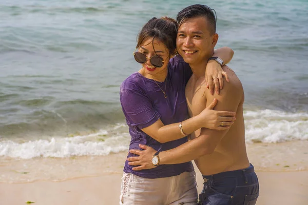 Summer holidays lifestyle portrait of young beautiful and sweet Asian Chinese couple in love walking on the beach together enjoying honeymoon trip in the beach smiling cheerful — 스톡 사진