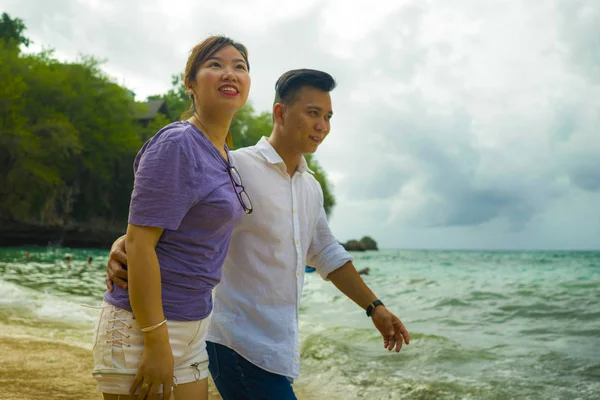 Summer holidays lifestyle portrait of young beautiful and sweet Asian Korean couple in love walking on the beach together enjoying honeymoon trip in the beach smiling cheerful — 스톡 사진