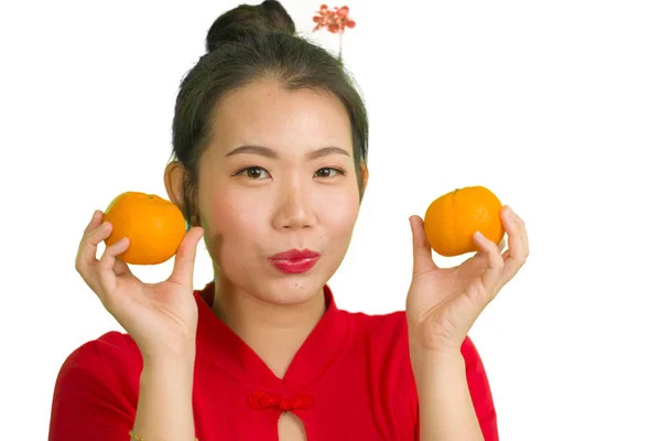 Jeune belle et heureuse femme asiatique dans la robe rouge traditionnelle du Nouvel An chinois tenant des fruits orange comme symbole de prospérité isolé sur fond blanc — Photo