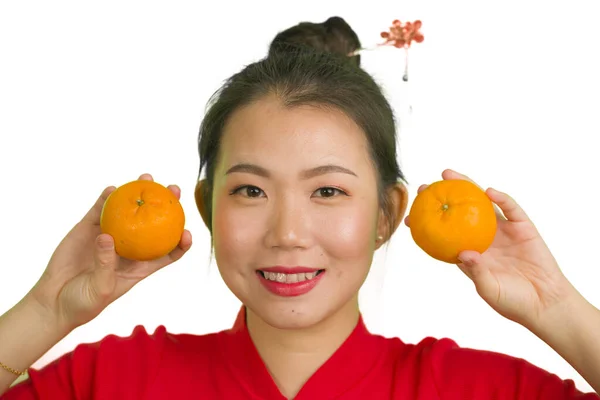 Νεαρή όμορφη και ευτυχισμένη Ασιάτισσα γυναίκα σε παραδοσιακό κινέζικο νέο έτος κόκκινο φόρεμα κρατώντας πορτοκαλί φρούτα ως σύμβολο της ευημερίας που απομονώνονται σε λευκό φόντο — Φωτογραφία Αρχείου