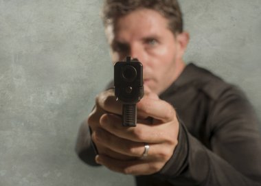 Çekici ve tehlikeli görünümlü tetikçinin grunge sinematik portresi ya da suç çetesi ve suç yaşam tarzı kavramına silah doğrultan gizli servis ajanı
