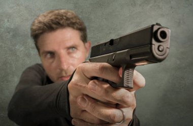 Çekici ve tehlikeli görünümlü tetikçinin grunge sinematik portresi ya da suç çetesi ve suç yaşam tarzı kavramına silah doğrultan gizli servis ajanı