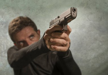 Çekici ve tehlikeli görünümlü tetikçinin grunge sinematik portresi ya da suç çetesi ve suç yaşam tarzı kavramına silah doğrultan gizli servis ajanı