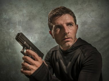 grunge cinematic portrait of attractive and dangerous looking hitman or secret service especial agent man in action pointing gun in crime mob and criminal lifestyle concept clipart