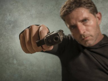 Çekici ve tehlikeli görünümlü tetikçinin grunge sinematik portresi ya da suç çetesi ve suç yaşam tarzı kavramına silah doğrultan gizli servis ajanı