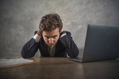 Depresyonda ve stresli İspanyol takım elbiseli ve kravatlı çekici iş adamı ofis bilgisayarında çalışırken yorgun düşmüş ve başı dertte olan yönetici olarak çok çalışmış.