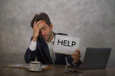 Depresyonda ve stresli takım elbiseli ve kravatlı çekici bir adam ezilmiş ofis bilgisayarında çalışıyor elinde not defteri tutarak hayal kırıklığına uğramış ve aşırı çalışılmış yardım istiyor.