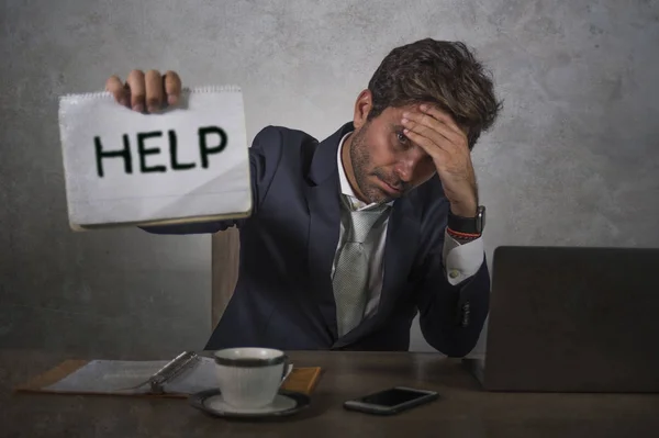 Depressed and stressed attractive hispanic man in suit and tie working overwhelmed office computer desk holding notepad asking for help frustrated and overworked — Stock Photo, Image