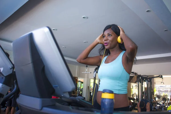 Estilo de vida de fitness retrato de la joven atractiva y feliz afroamericana negra entrenamiento de la mujer en el gimnasio todos haciendo ejercicio de la cinta de correr ajuste de auriculares escuchando música — Foto de Stock