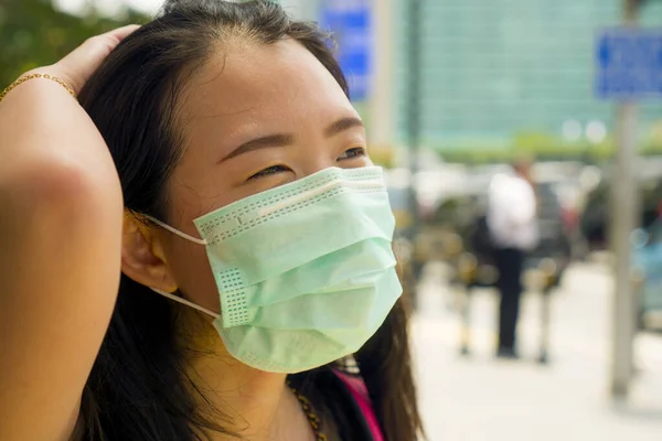 年轻美丽迷人的亚裔中国女学生头戴防护面罩，走在城市街道上，抵御中国科罗纳病毒大流行 — 图库照片