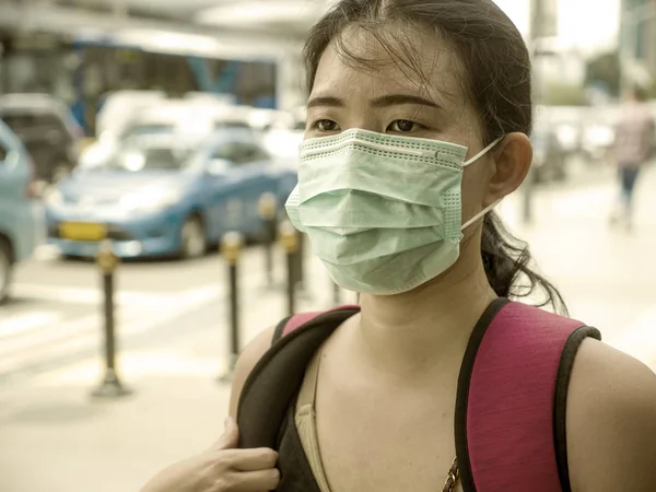 年轻美丽迷人的亚裔中国女学生头戴防护面罩，走在城市街道上，抵御中国科罗纳病毒大流行 — 图库照片