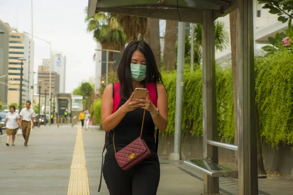 young beautiful and attractive Asian Chinese student woman walking on city street wearing protective facial mask against China Corona virus epidemic outbreak