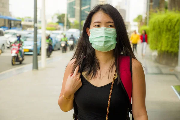 young beautiful and attractive Asian Chinese student woman walking on city street wearing protective facial mask against China Corona virus epidemic outbreak
