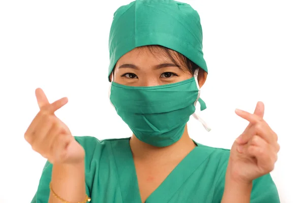 Young beautiful and happy Asian Chinese medicine doctor woman or hospital nurse in medical hat face mask and scrub doing fingers love sign smiling cheerful — 스톡 사진