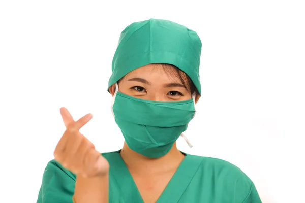 Isolated portrait of young beautiful and happy Asian Korean medicine doctor woman or hospital nurse in medical hat mask and scrub doing fingers love sign smiling cheerful — 스톡 사진