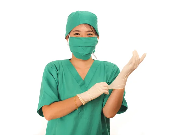 Young beautiful and happy medicine doctor or chief hospital nurse in green scrubs and surgey hat and mask wearing protective latex gloves — 스톡 사진